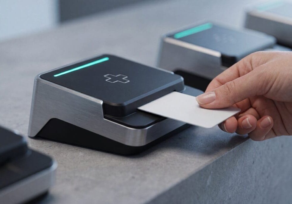 A patient using a smart card at a medical card reader terminal with a glowing green light, symbolizing EHR data interoperability, healthcare information technology, and the transfer of electronic health records.